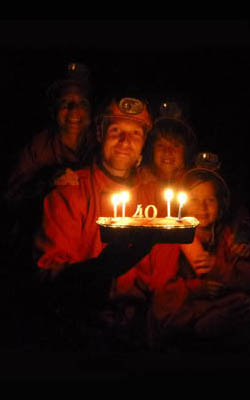 Homme qui souffle ses bougies dans une grotte avec sa famille